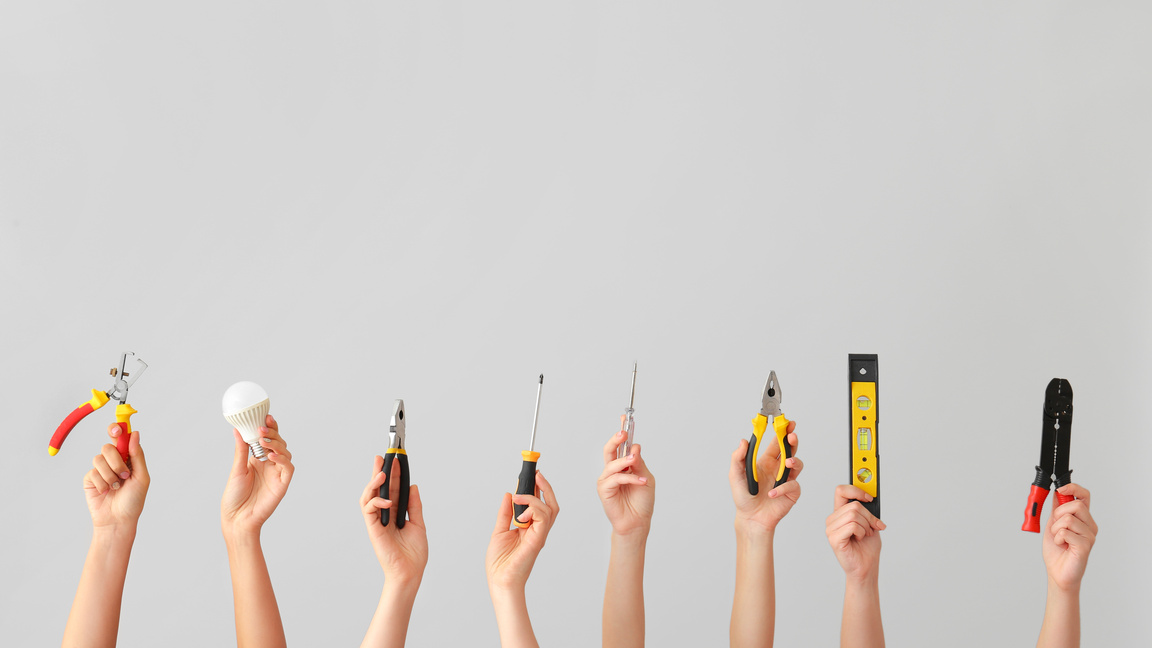 Female Hands with Electrician's Tools on Light Background